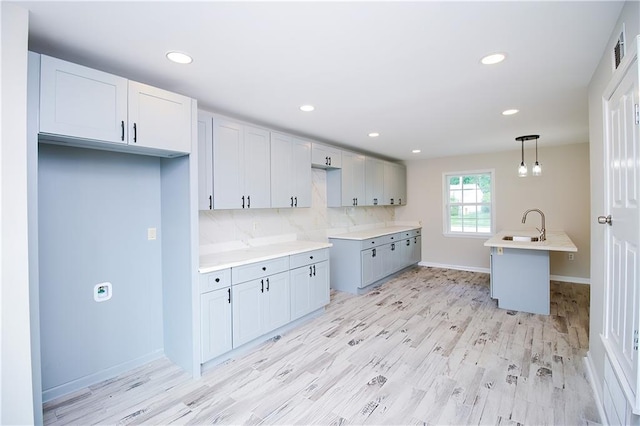 1304 Madewood Rd, La Place, LA 70068 - kitchen featuring recessed lighting, light wood-style floors, tasteful backsplash, decorative light fixtures, and light countertops