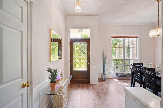 67061 Dolan St, Mandeville, LA 70471 - entrance foyer featuring a chandelier, light wood-style floors, a wainscoted wall, and crown molding