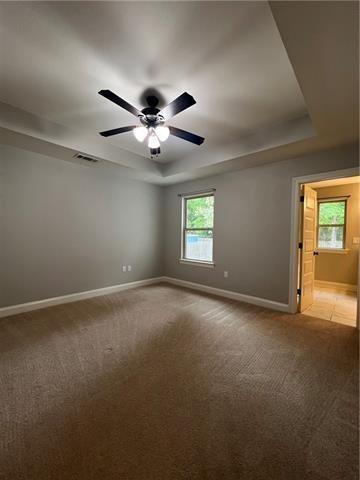 28623 Berry Todd Rd, Lacombe, LA 70445 - empty room featuring light colored carpet, ceiling fan, and a raised ceiling