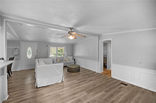 24473 Sanders Rd, Covington, LA 70435 - living area with a textured ceiling, a decorative wall, a ceiling fan, wood finished floors, and wainscoting