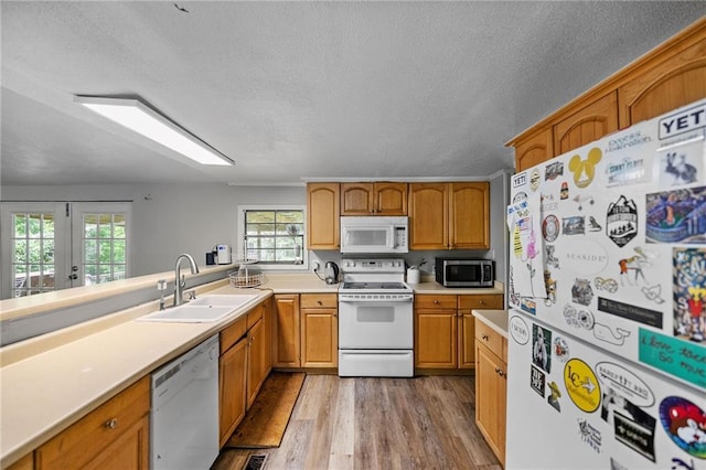 24473 Sanders Rd, Covington, LA 70435 - kitchen featuring white appliances, wood finished floors, light countertops, a textured ceiling, and brown cabinets