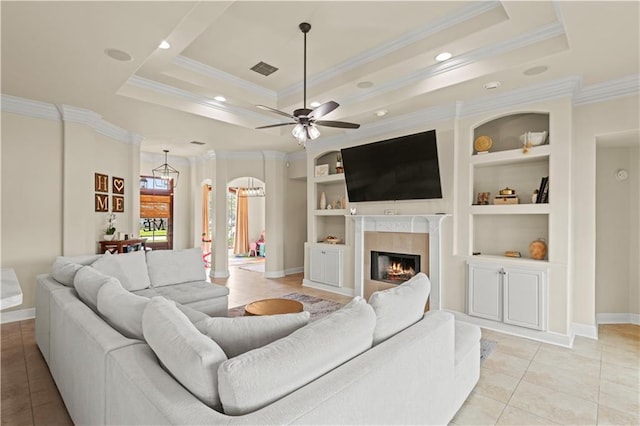 133 Oak Bend Dr, La Place, LA 70068 - living area with a tray ceiling, ornamental molding, light tile patterned flooring, a lit fireplace, and built in shelves