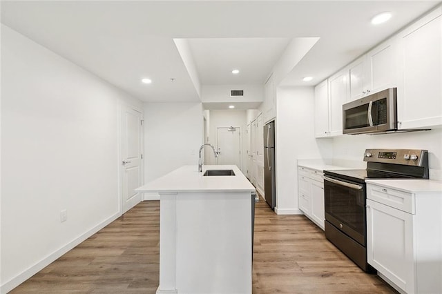 2100 Saint Thomas St Unit 202, New Orleans, LA 70130 - kitchen with stainless steel appliances, recessed lighting, a center island with sink, light wood-style floors, and white cabinets