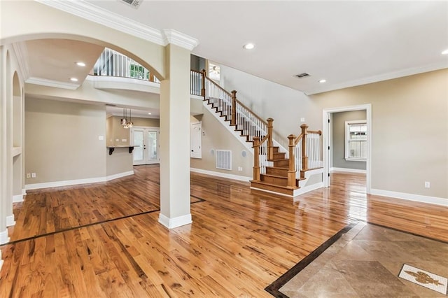4953 Music St, New Orleans, LA 70122 - foyer entrance featuring crown molding, light wood-type flooring, arched walkways, stairway, and recessed lighting