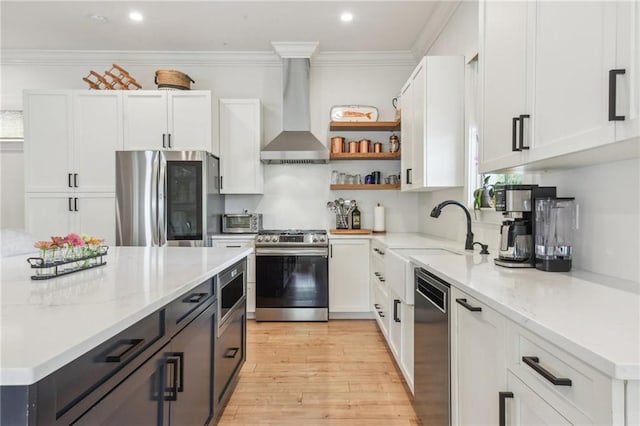 845 Pontalba St, New Orleans, LA 70124 - kitchen featuring stainless steel appliances, wall chimney exhaust hood, white cabinetry, light wood-style floors, and light stone counters