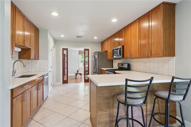 528 Carrollton Ave, Metairie, LA 70005 - kitchen featuring appliances with stainless steel finishes, light tile patterned floors, recessed lighting, brown cabinets, and light countertops