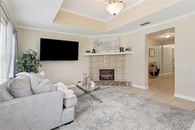 128 Marilyn Dr, Slidell, LA 70461 - living area with tile patterned floors, crown molding, a fireplace with raised hearth, and a tray ceiling