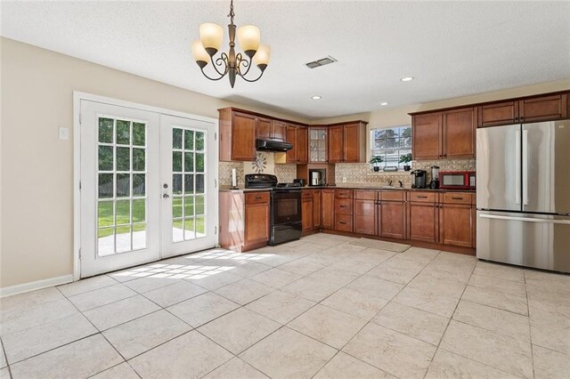 128 Marilyn Dr, Slidell, LA 70461 - kitchen with electric range, freestanding refrigerator, under cabinet range hood, a chandelier, and decorative backsplash