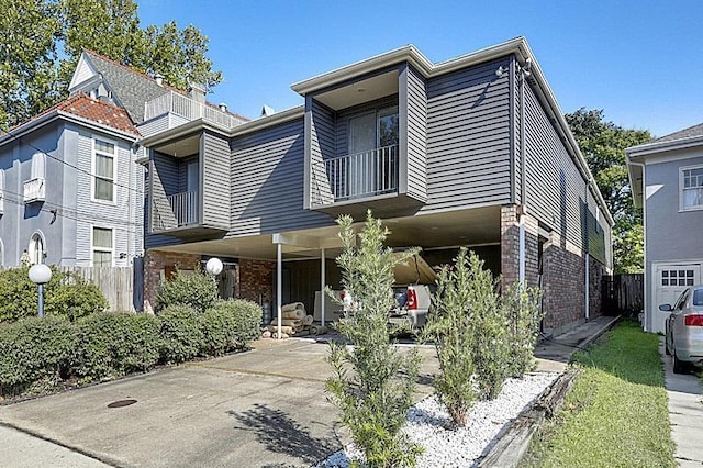 4433-35 Carondelet St, New Orleans, LA 70115 - view of property featuring a balcony, brick siding, a carport, and driveway