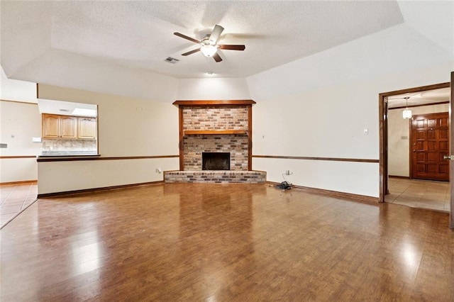 632 Brouilly Dr, Kenner, LA 70065 - unfurnished living room with a ceiling fan, light wood finished floors, a brick fireplace, and a textured ceiling