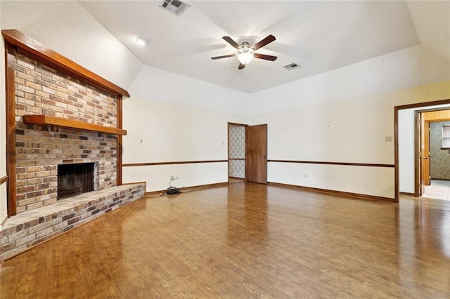 632 Brouilly Dr, Kenner, LA 70065 - unfurnished living room featuring wood finished floors, ceiling fan, a fireplace, vaulted ceiling, and a textured ceiling