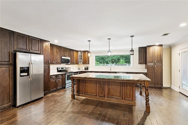 127 Herwig Bluff Rd, Slidell, LA 70461 - kitchen with appliances with stainless steel finishes, a breakfast bar, dark wood-style flooring, a center island, and crown molding