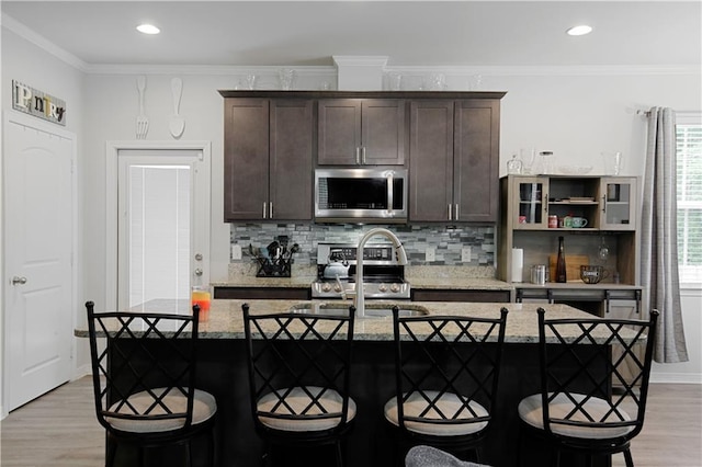 28794 Berry Todd Rd, Lacombe, LA 70445 - kitchen featuring appliances with stainless steel finishes, light wood-style floors, dark brown cabinetry, backsplash, and light stone countertops