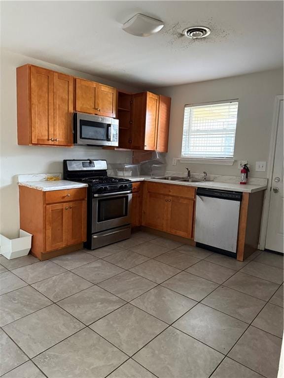 220810 Kraft Pl, New Orleans, LA 70114 - kitchen featuring stainless steel appliances, light countertops, brown cabinets, light tile patterned flooring, and open shelves