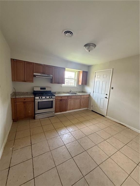 220810 Kraft Pl, New Orleans, LA 70114 - kitchen with stainless steel range with gas cooktop, under cabinet range hood, light countertops, and light tile patterned floors