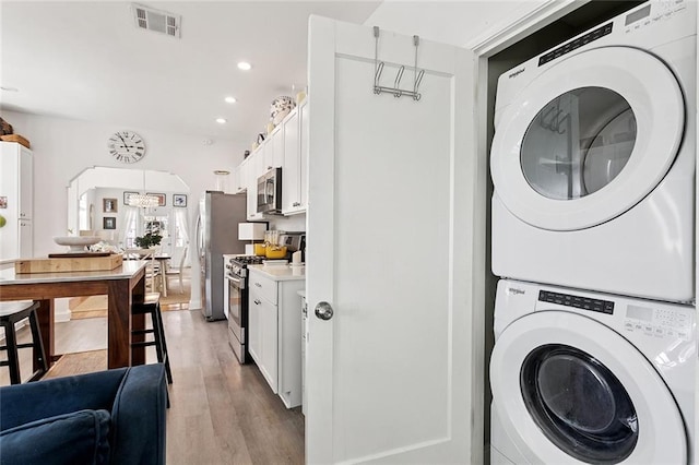 3116 Beaulieu St, Metairie, LA 70001 - washroom featuring stacked washer / dryer, light wood-style floors, recessed lighting, arched walkways, and a chandelier