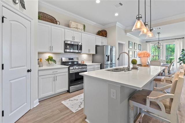 502 Terrace Lake Dr, Covington, LA 70435 - kitchen with stainless steel appliances, ornamental molding, an island with sink, a breakfast bar area, and tasteful backsplash