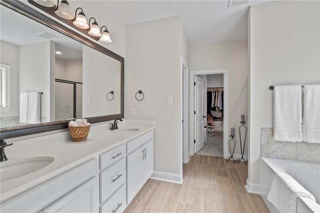 502 Terrace Lake Dr, Covington, LA 70435 - bathroom with wood finished floors, double vanity, a spacious closet, a bath, and a shower with door