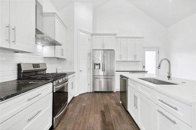 5502 Wilton Dr, New Orleans, LA 70122 - kitchen featuring appliances with stainless steel finishes, wall chimney exhaust hood, dark wood finished floors, white cabinetry, and backsplash
