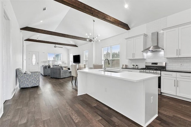 5502 Wilton Dr, New Orleans, LA 70122 - kitchen with wall chimney range hood, gas range, a ceiling fan, a center island with sink, and decorative backsplash