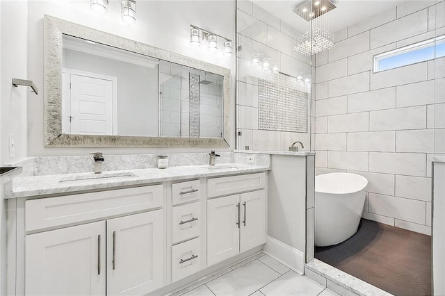 5502 Wilton Dr, New Orleans, LA 70122 - full bathroom featuring a freestanding bath, double vanity, a chandelier, marble look tile flooring, and tile walls
