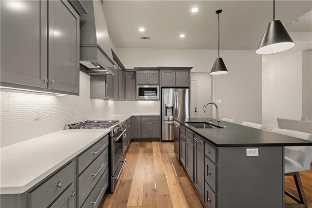 4028 Cypress Point Dr, Covington, LA 70433 - kitchen featuring stainless steel appliances, gray cabinets, a breakfast bar area, light wood-style flooring, and decorative backsplash