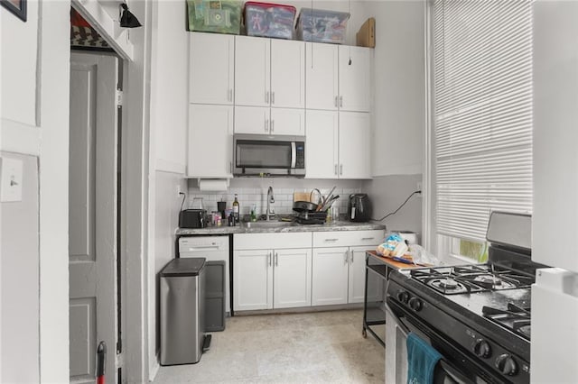 4149-51 Canal St, New Orleans, LA 70119 - kitchen with stainless steel microwave, range with gas stovetop, white cabinets, and backsplash