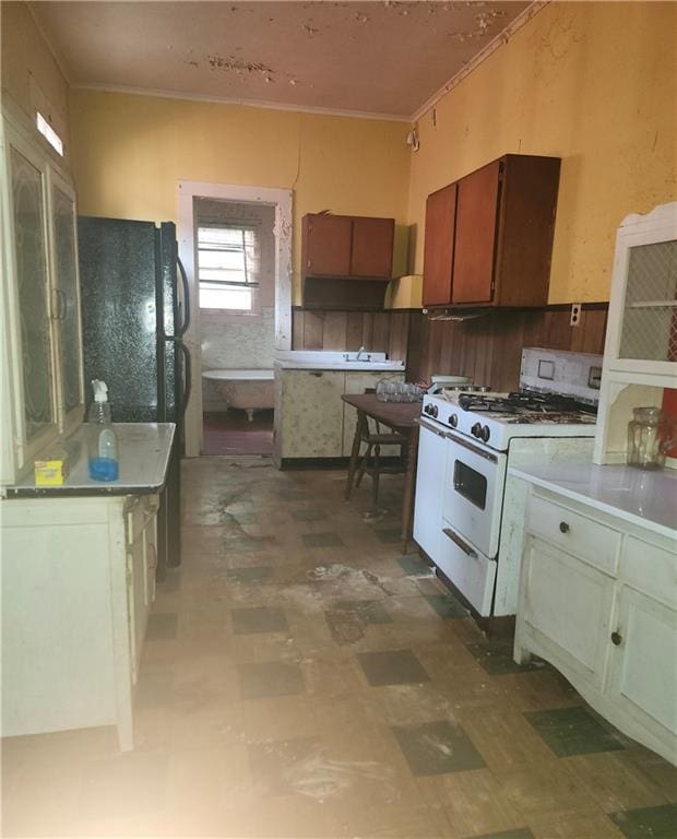 727 Montegut St, New Orleans, LA 70117 - kitchen featuring white range with gas stovetop, light floors, crown molding, and light countertops