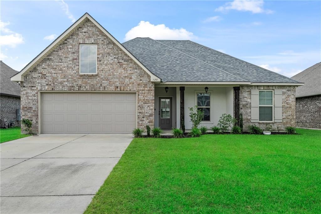 120 Cypresswood Dr, Belle Chasse, LA 70037 - view of front facade with a shingled roof, a front lawn, concrete driveway, and brick siding