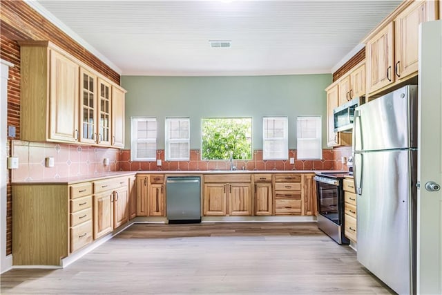 2970 College St, Slidell, LA 70458 - kitchen with stainless steel appliances, backsplash, glass insert cabinets, light brown cabinets, and light wood-style floors