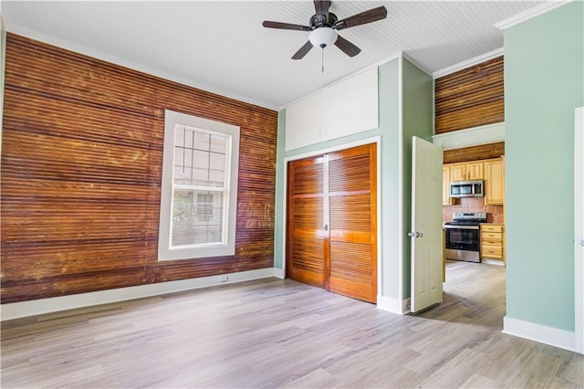 2970 College St, Slidell, LA 70458 - unfurnished bedroom with ornamental molding, a closet, light wood-type flooring, a ceiling fan, and wooden walls