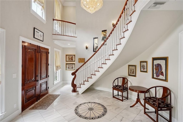 712 Stewart Ave, River Ridge, LA 70123 - entrance foyer with healthy amount of natural light, stairway, a towering ceiling, light marble finish floors, and a chandelier