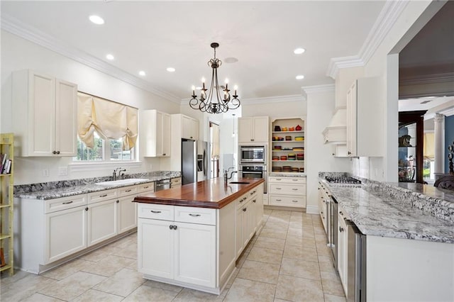 712 Stewart Ave, River Ridge, LA 70123 - kitchen with appliances with stainless steel finishes, open shelves, butcher block countertops, a chandelier, and a center island with sink