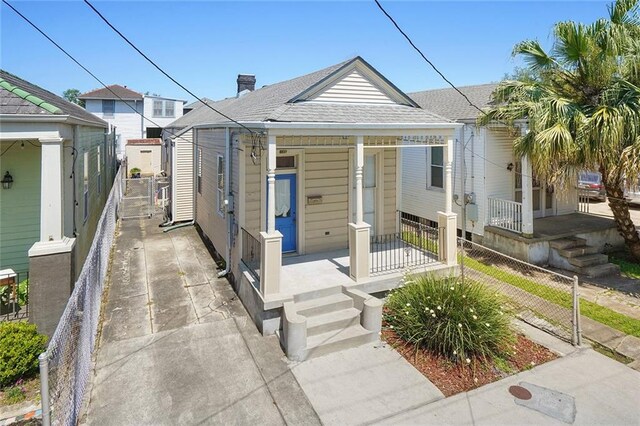 215 N Rendon St, New Orleans, LA 70119 - shotgun-style home featuring covered porch, a shingled roof, and a chimney