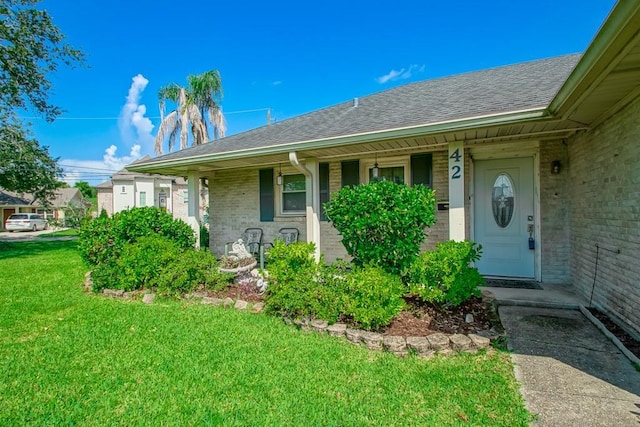 42 Hennessey Ct, River Ridge, LA 70123 - view of exterior entry featuring a lawn, a porch, a shingled roof, and brick siding