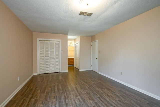 42 Hennessey Ct, River Ridge, LA 70123 - unfurnished bedroom featuring dark wood-style floors, a textured ceiling, and multiple closets