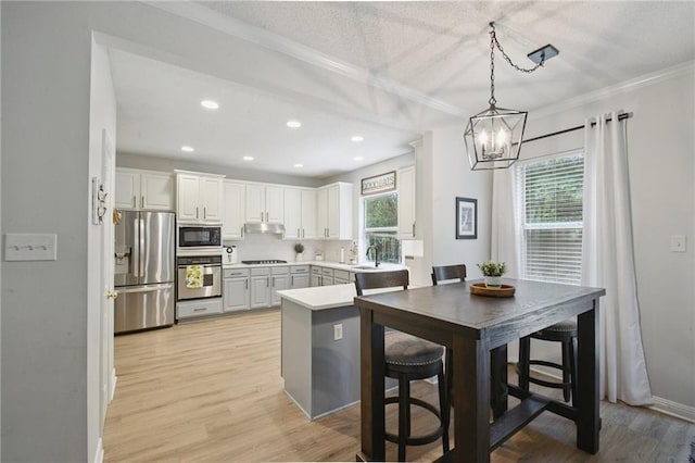 1125 Lori Dr, Slidell, LA 70461 - kitchen featuring black appliances, a chandelier, under cabinet range hood, ornamental molding, and hanging light fixtures