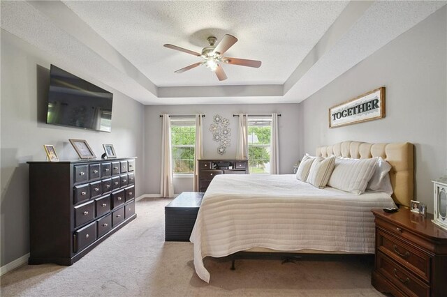 1125 Lori Dr, Slidell, LA 70461 - bedroom featuring a tray ceiling, light carpet, a textured ceiling, and ceiling fan
