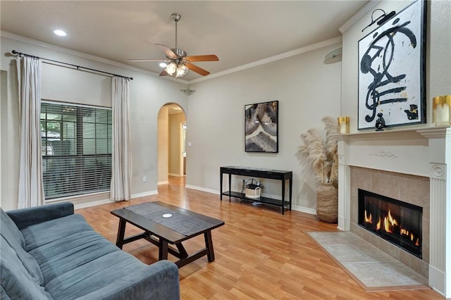 2523 Robin St, Slidell, LA 70460 - living room with a ceiling fan, arched walkways, crown molding, a tiled fireplace, and light wood finished floors