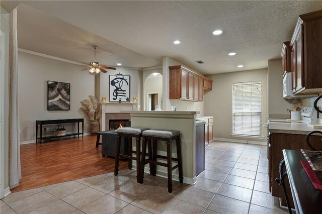 2523 Robin St, Slidell, LA 70460 - kitchen with light tile patterned floors, recessed lighting, a ceiling fan, a lit fireplace, and a kitchen breakfast bar
