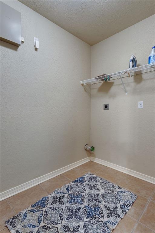 2523 Robin St, Slidell, LA 70460 - laundry room with electric dryer hookup, light tile patterned floors, a textured ceiling, and a textured wall