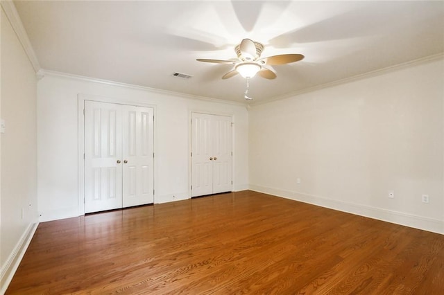 104 Acadian Ln, Mandeville, LA 70471 - unfurnished bedroom with multiple closets, ornamental molding, wood finished floors, and a ceiling fan