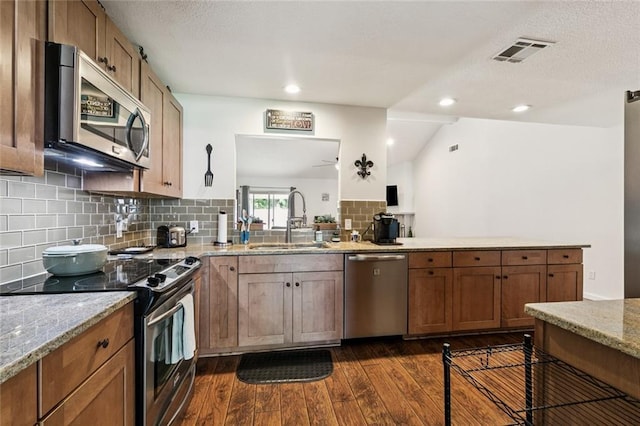 124 Brentwood Dr, Belle Chasse, LA 70037 - kitchen with stainless steel appliances, dark wood finished floors, decorative backsplash, brown cabinetry, and light stone counters