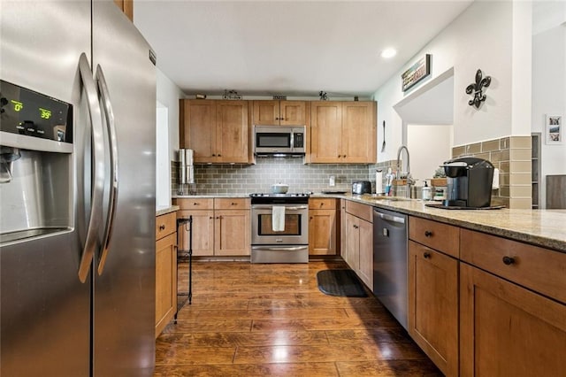 124 Brentwood Dr, Belle Chasse, LA 70037 - kitchen with stainless steel appliances, dark wood-style flooring, light stone counters, backsplash, and brown cabinetry