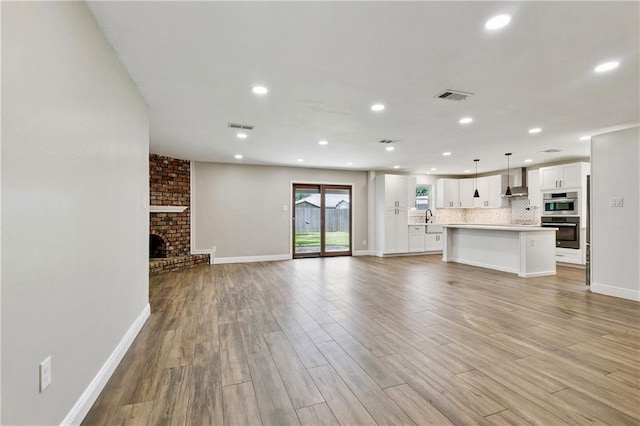 1424 Pecan Ave, Metairie, LA 70001 - unfurnished living room with light wood-type flooring, recessed lighting, and a brick fireplace