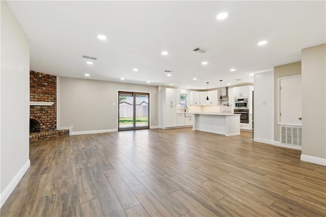 1424 Pecan Ave, Metairie, LA 70001 - unfurnished living room featuring wood finished floors, recessed lighting, and a brick fireplace