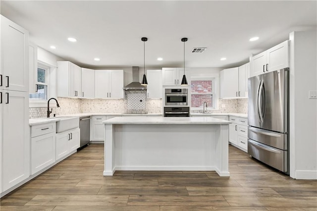 1424 Pecan Ave, Metairie, LA 70001 - kitchen with appliances with stainless steel finishes, wall chimney exhaust hood, a kitchen island, light countertops, and white cabinets
