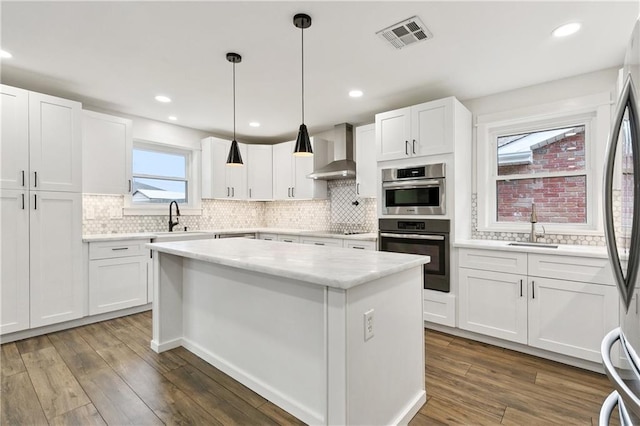 1424 Pecan Ave, Metairie, LA 70001 - kitchen featuring wall chimney range hood, white cabinets, a center island, backsplash, and stainless steel appliances