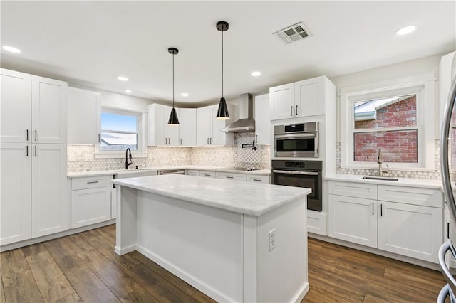 1424 Pecan Ave, Metairie, LA 70001 - kitchen featuring wall chimney exhaust hood, stainless steel appliances, white cabinetry, and recessed lighting