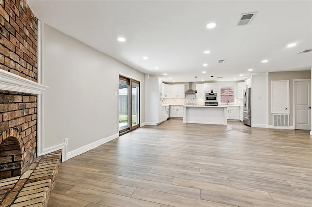 1424 Pecan Ave, Metairie, LA 70001 - unfurnished living room featuring a brick fireplace, recessed lighting, and light wood finished floors
